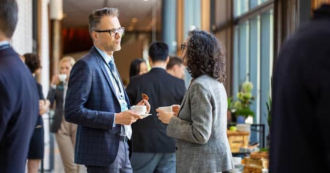 Men and women wearing suits and talking to each other