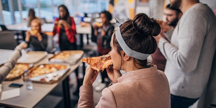 people eating pizza in a break room