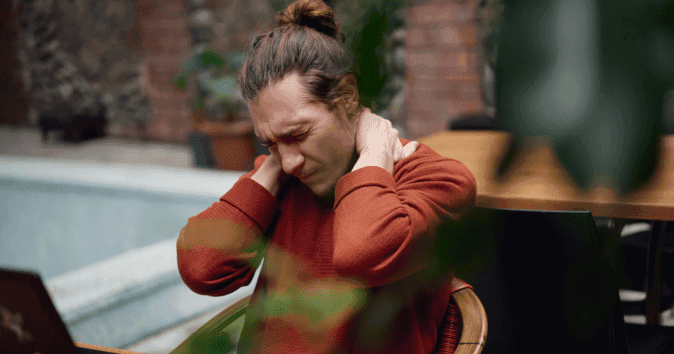 man rubbing sore neck at desk